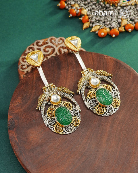 Noori two tone earrings are handcrafted in 92.5 sterling silver with kundan and gold highlights and carved green stone in the center. Style this one of a kind earring with your favourite ethnic or fusion outfits to complete the look.