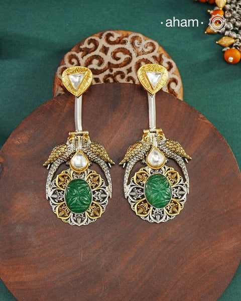Noori two tone earrings are handcrafted in 92.5 sterling silver with kundan and gold highlights and carved green stone in the center. Style this one of a kind earring with your favourite ethnic or fusion outfits to complete the look.