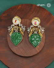 Noori two tone earrings are handcrafted in 92.5 sterling silver with kundan and gold highlights and carved green stone in the center.Style this one of a kind earring with your favourite ethnic or fusion outfits to complete the look.