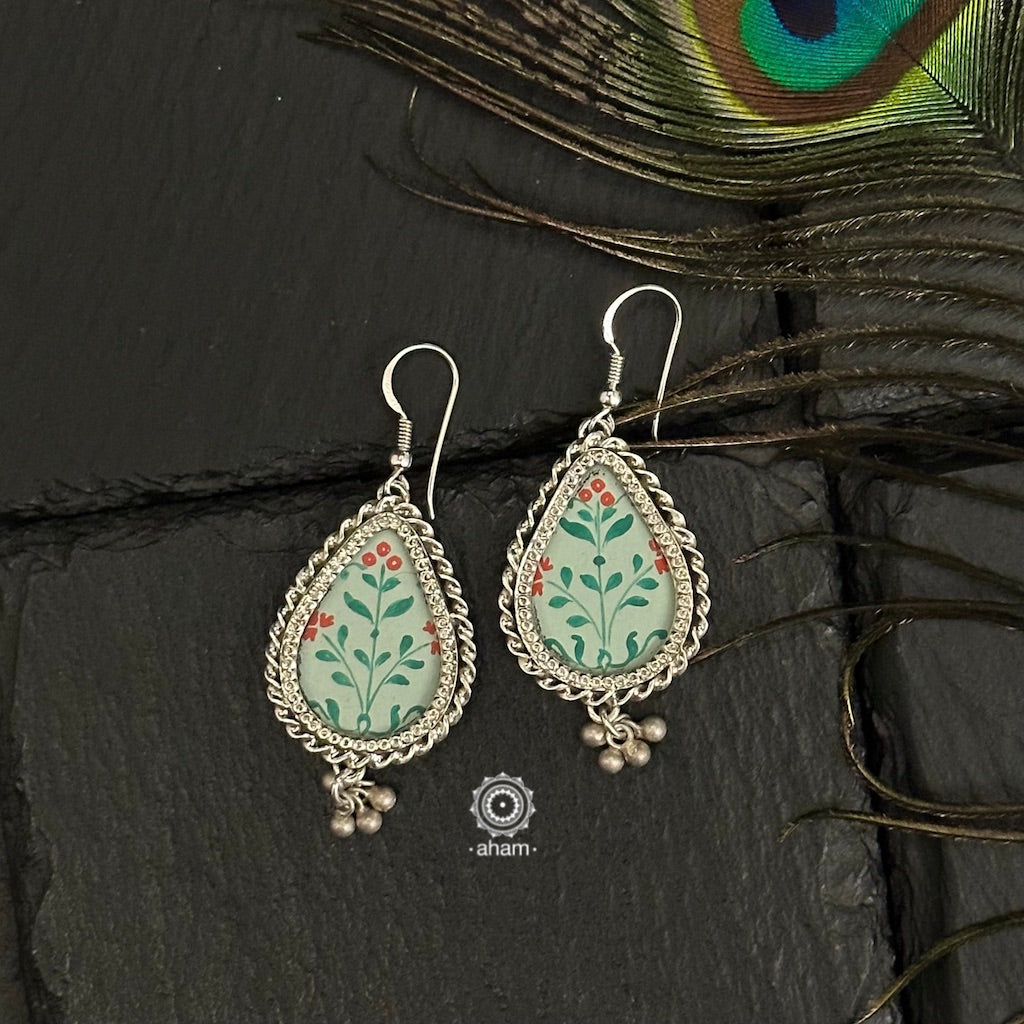 Hand painted silver drop earrings with intricate floral miniature painting done by skilful artisans enclosed with a glass top. Perfect everyday wear earrings. 