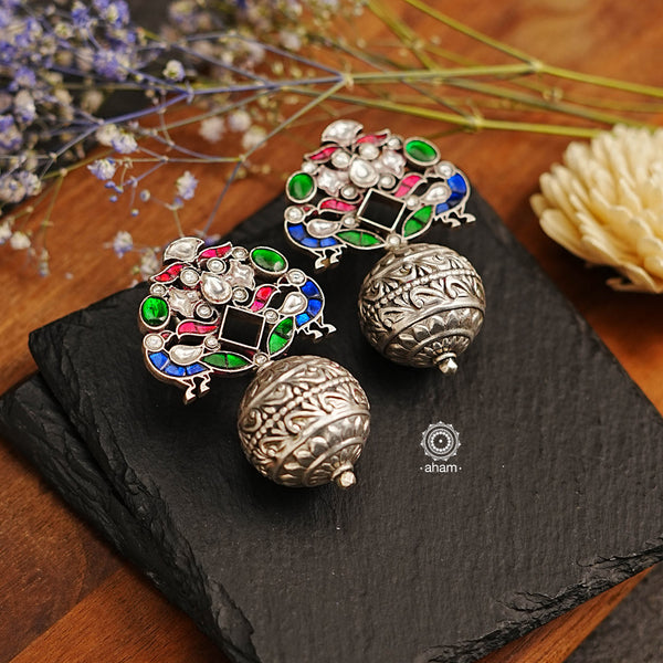 These Ira Peacock Drop Silver Earrings feature exquisite kundan work with a peacock motif, perfect for parties and evening soirees. Their lightweight ball drop construction ensures a comfortable fit. Elevate your outfit with this stunning piece of jewellery.