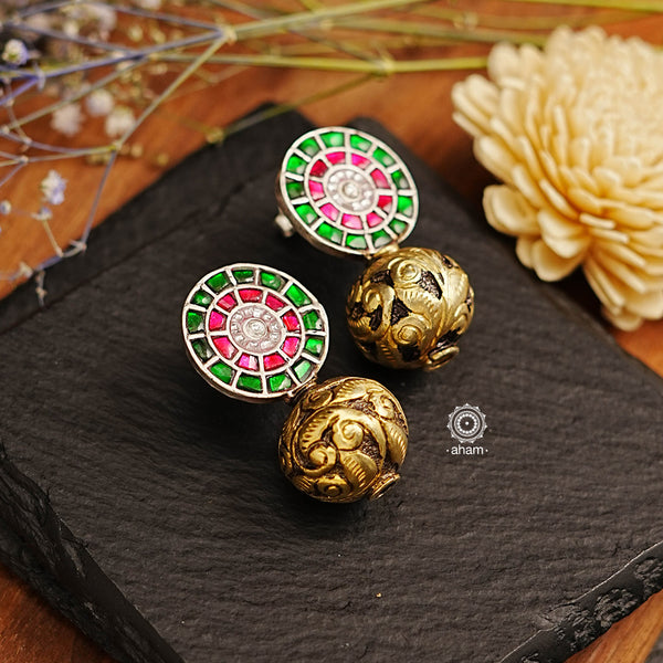 The Ira Drop Silver Earrings feature dual tones of silver and gold polish for a stunning look. The earrings are crafted in 92.5 silver and embellished with green and rani pink kundan with chitai work drop ball. A luxurious and elegant accessory perfect for any occasion.