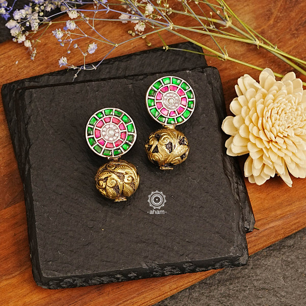 The Ira Drop Silver Earrings feature dual tones of silver and gold polish for a stunning look. The earrings are crafted in 92.5 silver and embellished with green and rani pink kundan with chitai work drop ball. A luxurious and elegant accessory perfect for any occasion.