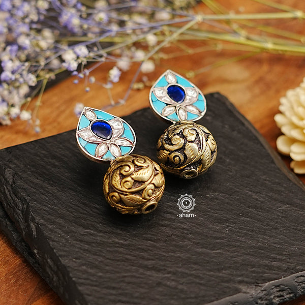 The Ira Drop Silver Earrings feature dual tones of silver and gold polish for a stunning look. The earrings are embellished with turquoise and kundan highlighted with chitai work drop ball. A luxurious and elegant accessory perfect for any occasion.