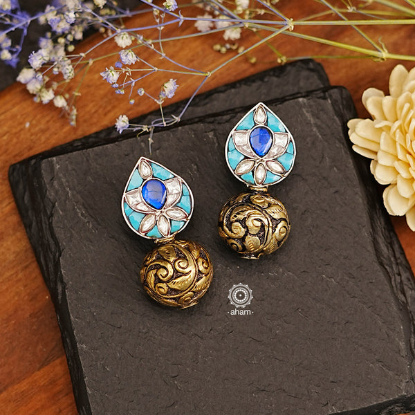 The Ira Drop Silver Earrings feature dual tones of silver and gold polish for a stunning look. The earrings are embellished with turquoise and kundan highlighted with chitai work drop ball. A luxurious and elegant accessory perfect for any occasion.