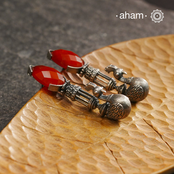 Enhance your style with these Ira Carnelian Peacock Silver Earrings. The stunning peacock design and vibrant carnelian stone create a unique and understated look. Handcrafted in 92.5 silver, these earrings are a perfect addition to any jewellery collection.