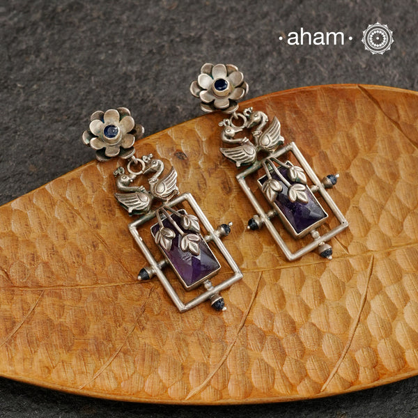 Elevate your style with our Ira Double Peacock Silver Earrings. These stylish earrings feature a stunning purple stone, surrounded by intricate peacock designs crafted in 92.5 silver. Add a touch of elegance to any outfit with these beautiful earrings.