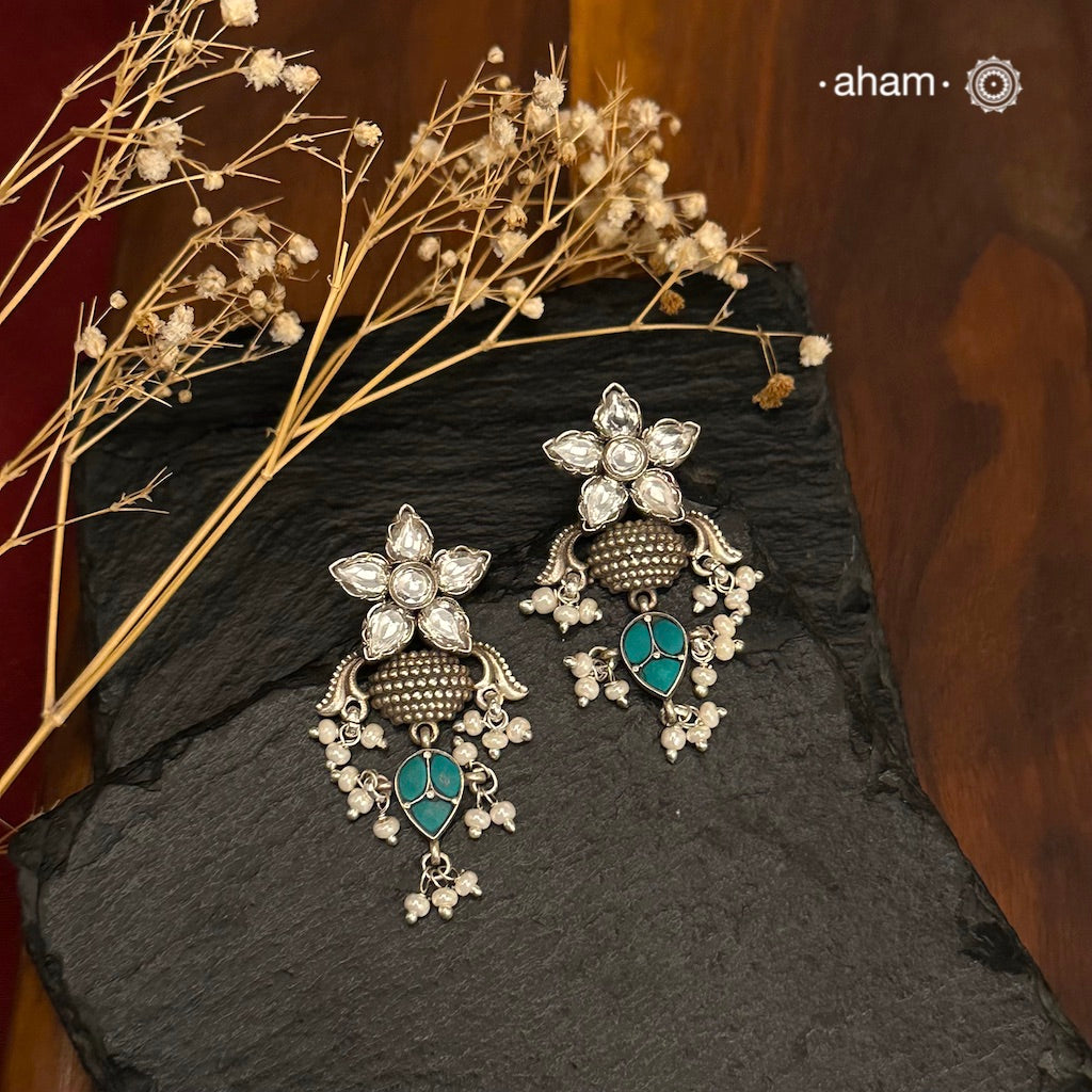 Elevate your style with our Ira Silver Earrings. Adorned with a stunning Kundan flower and turquoise drop, they add a touch of sparkle to any occasion. Made with 92.5 silver, these earrings are the perfect mix of elegance and charm. Shop now and make a statement.