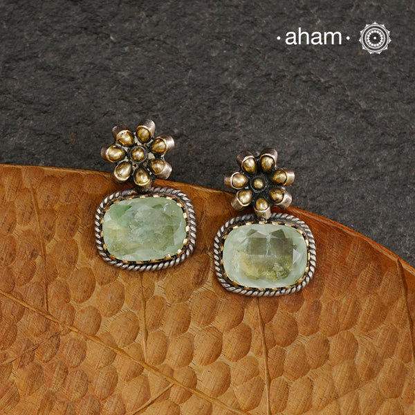 Elevate your look with our Ira Silver Earrings. These expertly crafted 92.5 silver earrings feature delicate flower detailing in dull gold and a stunning sea green stone drop. Perfect for adding a touch of elegance to any outfit.