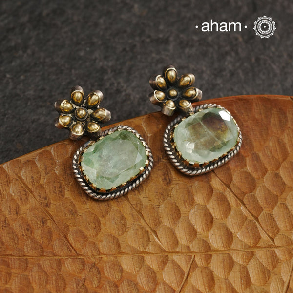 Elevate your look with our Ira Silver Earrings. These expertly crafted 92.5 silver earrings feature delicate flower detailing in dull gold and a stunning sea green stone drop. Perfect for adding a touch of elegance to any outfit.