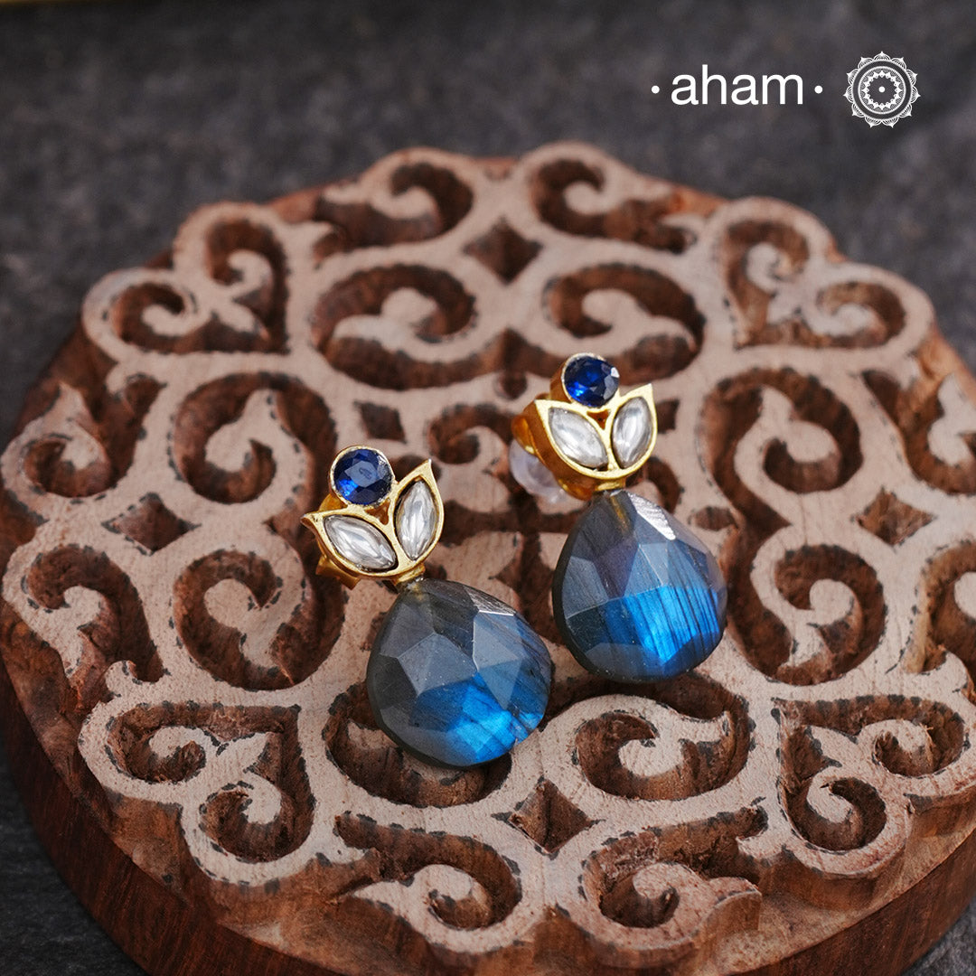 These elegant silver earrings feature a natural labradorite gemstone, accented with a white kundan gold polish. The labradorite stone adds a touch of natural beauty, while the kundan gold polish gives a sophisticated shine. Perfect for adding a touch of elegance to any outfit.