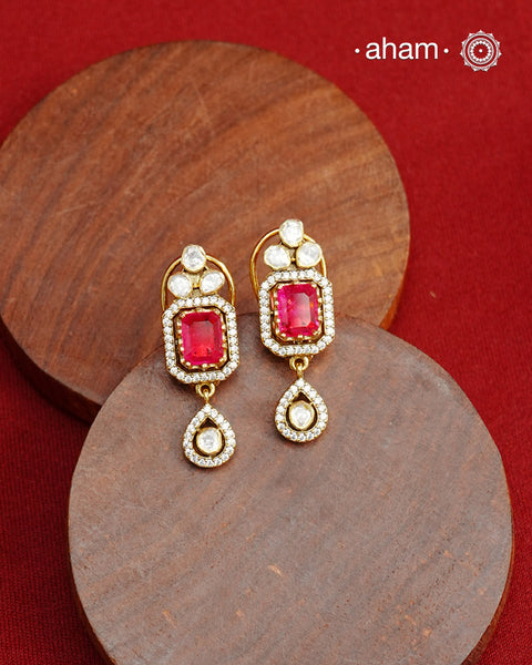 Expertly crafted studs in 92.5% sterling silver with a fine gold polish finish, elegantly set with brilliant moissanite stones and a deep pink lustrous red stone in the center. Designed to offer lasting shine and sophistication making them a perfect choice for special occasions. &nbsp;