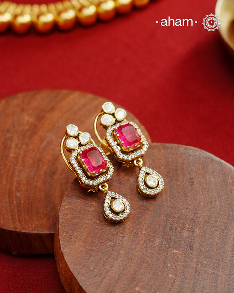 Expertly crafted studs in 92.5% sterling silver with a fine gold polish finish, elegantly set with brilliant moissanite stones and a deep pink lustrous red stone in the center. Designed to offer lasting shine and sophistication making them a perfect choice for special occasions. &nbsp;