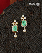 Thoughtfully crafted in 92.5 sterling silver with a fine gold polish, these earrings celebrate timeless design and fine craftsmanship. A luminous green stone takes center stage, framed by shimmering moissanites that catch the light beautifully. Refined, versatile, and easy to wear, they are designed to become a favourite for years to come.