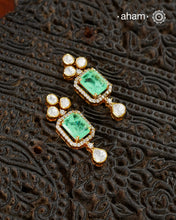 Thoughtfully crafted in 92.5 sterling silver with a fine gold polish, these earrings celebrate timeless design and fine craftsmanship. A luminous green stone takes center stage, framed by shimmering moissanites that catch the light beautifully. Refined, versatile, and easy to wear, they are designed to become a favourite for years to come.