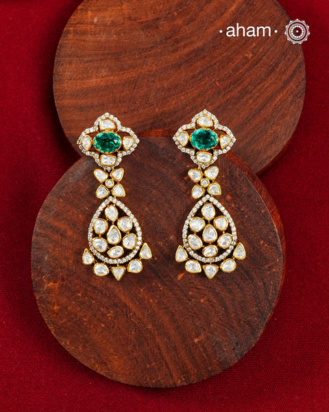A timeless blend of brilliance and elegance, these handcrafted earrings are crafted in 92.5 sterling silver and finished with a luxurious gold polish. Designed with an intricate arrangement of sparkling moissanite stones, the earrings are highlighted by vibrant emerald-hued centre stones that lend a rich pop of colour and sophistication.

The graceful floral and teardrop-inspired silhouette is accentuated with finely set moissanite, creating exceptional sparkle from every angle. Refined yet striking, these 
