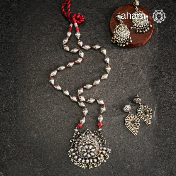 The Mewad Silver Neckpiece exemplifies superior craftsmanship with its intricate pendant design featuring a refined pearl setting. Meticulously crafted from 92.5 sterling silver, this piece combines traditional artistry with the distinctive texture of a dholki bead chain. The pendant's detailed silverwork demonstrates exceptional technical precision, creating a sophisticated adornment that honours traditional metalsmithing techniques while offering contemporary elegance.