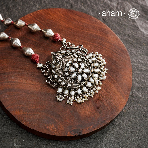 The Mewad Silver Neckpiece exemplifies superior craftsmanship with its intricate pendant design featuring a refined pearl setting. Meticulously crafted from 92.5 sterling silver, this piece combines traditional artistry with the distinctive texture of a dholki bead chain. The pendant's detailed silverwork demonstrates exceptional technical precision, creating a sophisticated adornment that honours traditional metalsmithing techniques while offering contemporary elegance.