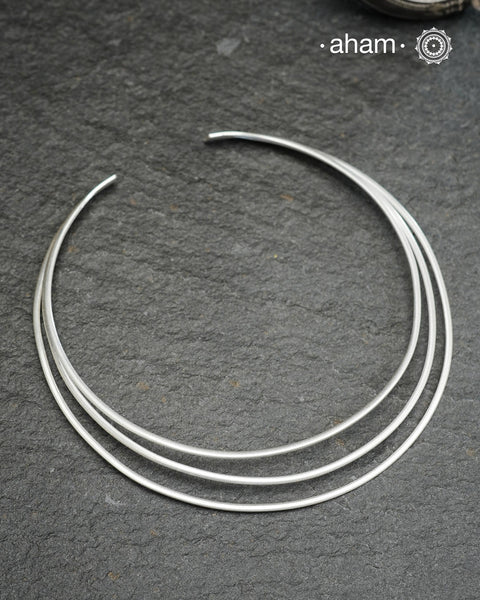Discover understated luxury with this three-line silver hasli, a masterfully crafted collar piece in 92.5 sterling silver. Its clean, geometric design bridges the gap between casual and formal wear—pair it effortlessly with your favourite shirt or dress. The versatile open framework welcomes customization; add a pendant to create a signature look or wear it bare for refined minimalism. Handcrafted with precision, this piece embodies timeless elegance and adaptability for the discerning jewellery enthusiast.