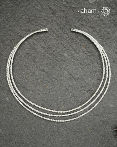 Discover understated elegance with this three-line twisted silver hasli, a masterfully crafted collar piece in 92.5 sterling silver. Its clean, geometric design bridges the gap between casual and formal wear—pair it effortlessly with your favourite shirt or dress. The versatile open framework welcomes customization; add a pendant to create a signature look or wear it bare for refined minimalism. Handcrafted with precision, this is a timeless piece you would love to wear.