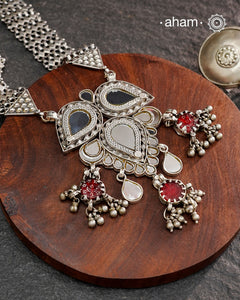 This Mewad White Glass Silver Neckpiece showcases a beautifully crafted glass pendant made by skilled karigars in Barmer, accented with vintage red glass drops. Complemented by elegant silver side bands, it reflects exquisite craftsmanship and adds a graceful, timeless charm to your jewelry collection.