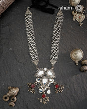 This Mewad White Glass Silver Neckpiece showcases a beautifully crafted glass pendant made by skilled karigars in Barmer, accented with vintage red glass drops. Complemented by elegant silver side bands, it reflects exquisite craftsmanship and adds a graceful, timeless charm to your jewelry collection.