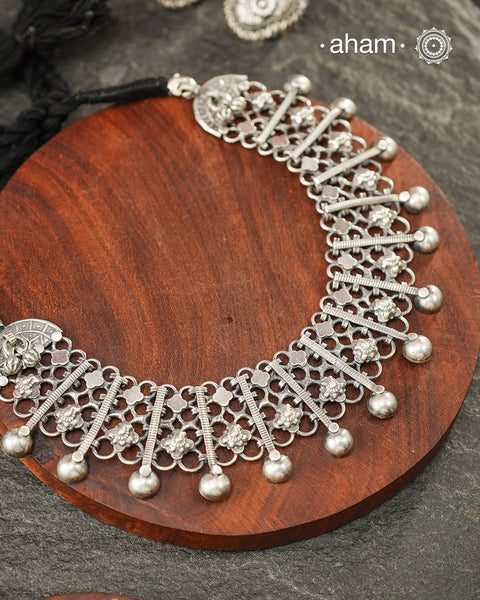 Graceful and intricately detailed, this handcrafted silver neckpiece crafted in 92.5 silver is designed to make a statement through its beautifully balanced composition. Delicate openwork, sculpted floral accents, and polished silver drops come together in a rhythmic pattern that lends the piece depth, texture, and movement.

Despite its striking appearance, the neckpiece is lightweight and comfortable to wear, making it an effortless choice for both everyday dressing and special occasions. 