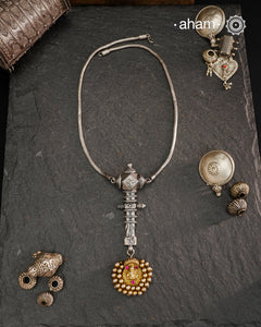 This Krishna Tribal Silver Neckpiece is a unique creation combining a vintage belt buckle and a vintage Krishna hair pin into a distinctive pendant. Expertly crafted in silver and finished with a woven chain, it offers a rare blend of heritage elements and artisanal craftsmanship, making it a remarkable statement piece for collectors and connoisseurs of fine jewellery.