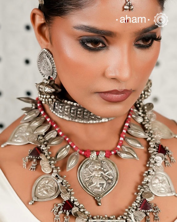 This Vintage Kal Bhairav Silver Neckpiece features a traditional central pendant symbolizing Kal Bhairav, flanked by bud-shaped beads on either side. Threaded on red cotton, it combines heritage craftsmanship with comfortable wear. Each piece reflects timeless artistry, offering a unique connection to history and culture for discerning collectors and enthusiasts.