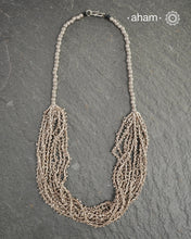 The Odhisa Dhaan Mala Silver Neckpiece is a masterful vintage creation featuring multiple strands of delicately crafted rice-shaped silver beads. Each bead is meticulously formed, reflecting exceptional craftsmanship rooted in Odisha’s rich heritage. This intricate neckpiece offers a timeless elegance, perfect for those who appreciate artisanal detail and cultural artistry in their jewellery collection.