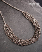 The Odhisa Dhaan Mala Silver Neckpiece is a masterful vintage creation featuring multiple strands of delicately crafted rice-shaped silver beads. Each bead is meticulously formed, reflecting exceptional craftsmanship rooted in Odisha’s rich heritage. This intricate neckpiece offers a timeless elegance, perfect for those who appreciate artisanal detail and cultural artistry in their jewellery collection.