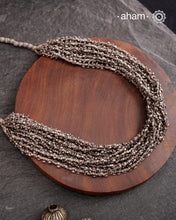 The Odhisa Dhaan Mala Silver Neckpiece is a masterful vintage creation featuring multiple strands of delicately crafted rice-shaped silver beads. Each bead is meticulously formed, reflecting exceptional craftsmanship rooted in Odisha’s rich heritage. This intricate neckpiece offers a timeless elegance, perfect for those who appreciate artisanal detail and cultural artistry in their jewellery collection.