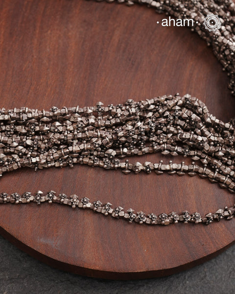 The Odhisa Dhaan Mala Silver Neckpiece is a masterful vintage creation featuring multiple strands of delicately crafted rice-shaped silver beads. Each bead is meticulously formed, reflecting exceptional craftsmanship rooted in Odisha’s rich heritage. This intricate neckpiece offers a timeless elegance, perfect for those who appreciate artisanal detail and cultural artistry in their jewellery collection.