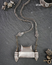 This handcrafted silver neckpiece features a revered Shiva lingam design, rooted in the spiritual traditions of the Lingayat community. The piece showcases meticulous artisanal craftsmanship, with its distinctive projection elegantly referencing Nandi, the sacred bull. Historically significant among Shaivite practitioners, particularly from Karnataka, this vintage-inspired silver casket serves as both a devotional ornament and cultural emblem. 
