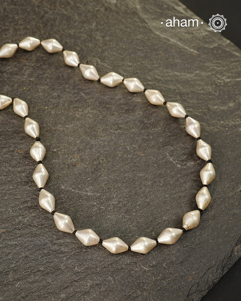 Silver Dholki/ Wax Beads coated with silver foil with black adjustable thread. Also known as Bor Mala