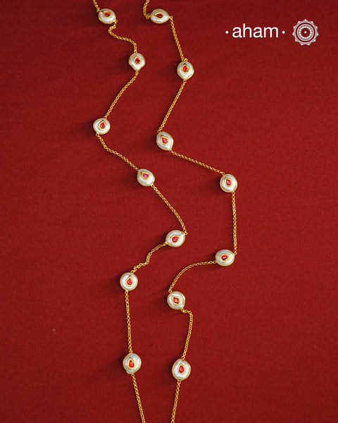 This handcrafted silver neckpiece features exquisite mother of pearl and intricate kundan inlay work, enhanced with a refined gold polish. Designed for versatility, it can be worn as a single long line or doubled for a layered look, making it a sophisticated addition to any jewellery collection.