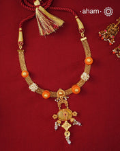Crafted in 92.5 sterling silver with a radiant 24 carat gold polish, this handcrafted neckpiece brings together traditional craftsmanship and contemporary elegance. The intricately woven chain is accented with vibrant coral-toned beads, delicate freshwater pearl clusters, and an ornate statement pendant featuring intricate hand-finished detailing. Soft faceted natural stone drops add a graceful touch, lending subtle movement and refined charm to the design.