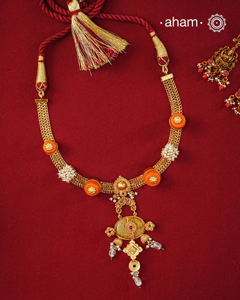 Crafted in 92.5 sterling silver with a radiant 24 carat gold polish, this handcrafted neckpiece brings together traditional craftsmanship and contemporary elegance. The intricately woven chain is accented with vibrant coral-toned beads, delicate freshwater pearl clusters, and an ornate statement pendant featuring intricate hand-finished detailing. Soft faceted natural stone drops add a graceful touch, lending subtle movement and refined charm to the design.