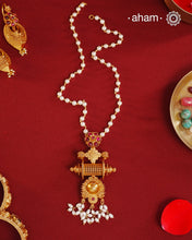 Inspired by the intricate designs of South temple art, this neckpiece is expertly crafted from 92.5% pure silver and finished with a refined dull gold polish. Complemented by a delicate pearl chain, it embodies a harmonious blend of traditional craftsmanship and timeless elegance, ideal for enhancing any special occasion ensemble.