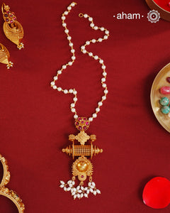 Inspired by the intricate designs of South temple art, this neckpiece is expertly crafted from 92.5% pure silver and finished with a refined dull gold polish. Complemented by a delicate pearl chain, it embodies a harmonious blend of traditional craftsmanship and timeless elegance, ideal for enhancing any special occasion ensemble.