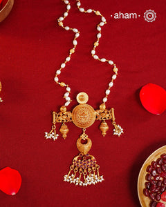 Inspired by the intricate designs of South temple art, this neckpiece is expertly crafted from 92.5% pure silver and finished with a refined dull gold polish. Complemented by a delicate pearl chain, it embodies a harmonious blend of traditional craftsmanship and timeless elegance, ideal for enhancing any special occasion ensemble.