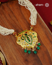 Crafted in 92.5 sterling silver with a radiant 24 carat gold polish, this handcrafted neckpiece draws inspiration from the divine adornments of Shrinathji. The intricately detailed pendant is embellished with traditional kundan work, vibrant emerald and ruby-toned accents, and graceful pearl detailing, while rich green stone drops add a striking finish. Multiple strands of delicate faux pearls complete the design, lending it an elegant and regal presence.