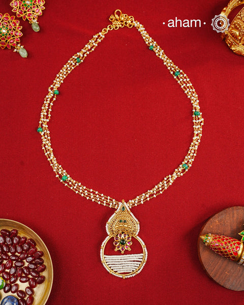 Inspired by the intricate designs of South temple art, this neckpiece is expertly crafted from 92.5% pure silver and finished with a refined dull gold polish. Complemented by a delicate pearl chain, it embodies a harmonious blend of traditional craftsmanship and timeless elegance, ideal for enhancing any special occasion ensemble.