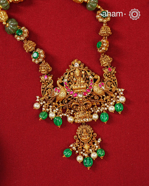 Inspired by the grandeur of South Indian temple jewellery, this exquisite necklace is handcrafted in 92.5 sterling silver and finished with a rich gold polish. At its heart sits Goddess Lakshmi, gracefully seated on a lotus, symbolising prosperity, abundance, and divine blessings. Flanked by intricately sculpted peacock motifs and surrounded by delicate floral scrollwork, the pendant is a celebration of traditional nakshi craftsmanship.