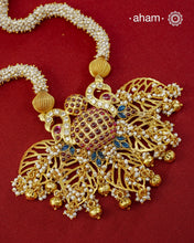 Crafted in 92.5 sterling silver with an opulent&nbsp;gold polish, this handcrafted neckpiece is a striking celebration of Indian artistry. A magnificent statement pendant, adorned with shimmering kundan work, vibrant ruby and sapphire-toned stones, and delicate pearl embellishments, is beautifully suspended from multiple strands of handwoven freshwater pearls. Intricate openwork detailing and graceful dangling accents add depth, movement, and timeless elegance to the design.