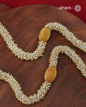 Crafted in 92.5 sterling silver with an opulent&nbsp;gold polish, this handcrafted neckpiece is a striking celebration of Indian artistry. A magnificent statement pendant, adorned with shimmering kundan work, vibrant ruby and sapphire-toned stones, and delicate pearl embellishments, is beautifully suspended from multiple strands of handwoven freshwater pearls. Intricate openwork detailing and graceful dangling accents add depth, movement, and timeless elegance to the design.