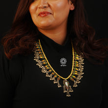 Handcrafted tribal glass silver neckpiece with statement ghungroos. Created by threading together multiple tribal pieces with green amd red stones giving it a vibrant look. This necklace truly exemplifies the continuity of the traditional designs. 