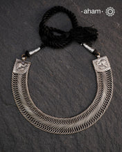 This Tribal Flat Silver Neckpiece features intricate wire weaving that contours elegantly around the neck. Crafted from high-quality silver, its timeless design complements both Indian traditional attire and contemporary western outfits, making it a versatile addition to any jewellery collection.