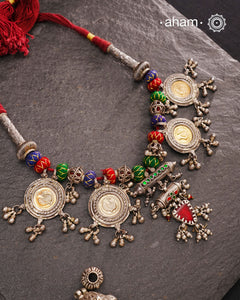 This Tribal Silver Neckpiece is a captivating blend of vintage charm and skilled craftsmanship. Featuring a central amulet with a delicate glass drop, it is beautifully complemented by four coin-shaped amulets stamped with intricate peacock motifs, two on each side. Carefully threaded together and crafted in silver, this unique piece adds a timeless, elegant touch to your collection, perfect for those who value heritage and artistry in their jewellery.