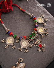 This Tribal Silver Neckpiece is a captivating blend of vintage charm and skilled craftsmanship. Featuring a central amulet with a delicate glass drop, it is beautifully complemented by four coin-shaped amulets stamped with intricate peacock motifs, two on each side. Carefully threaded together and crafted in silver, this unique piece adds a timeless, elegant touch to your collection, perfect for those who value heritage and artistry in their jewellery.